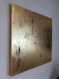 a gold painting hangs on a wall in a room