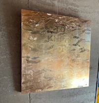 a piece of metal hanging on a wall next to a concrete wall